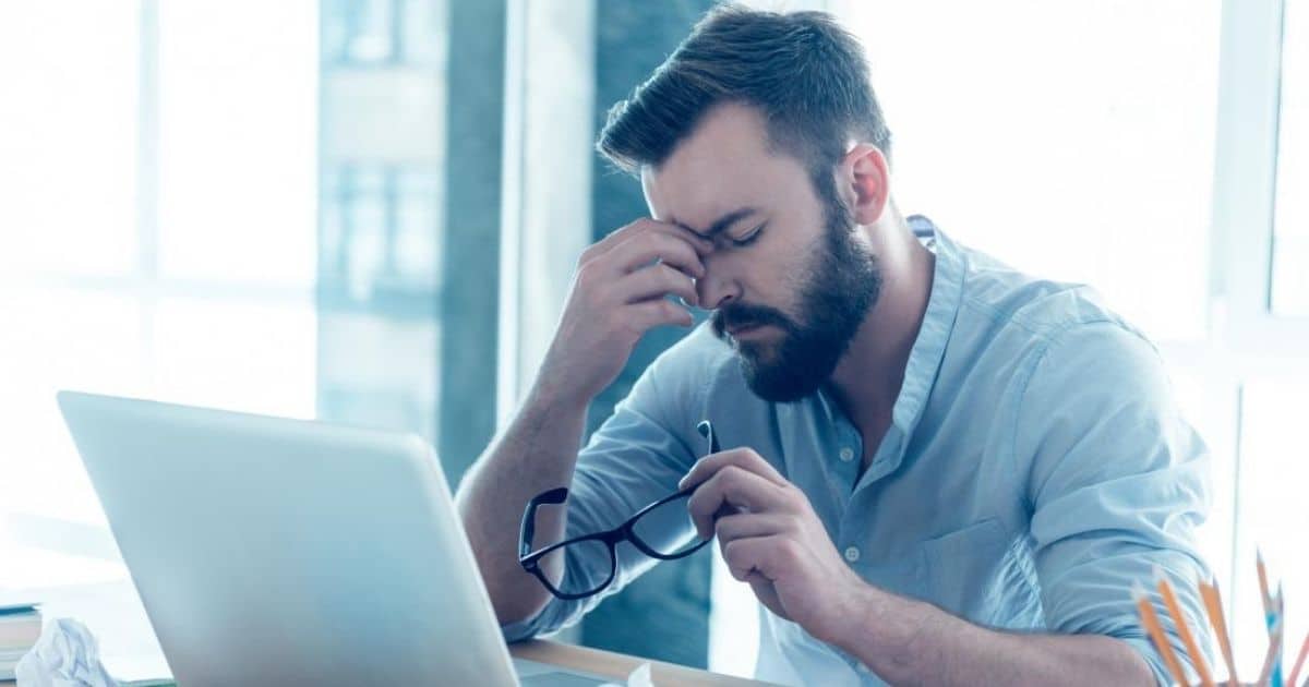 Tired businessman rubbing his eyes at a laptop