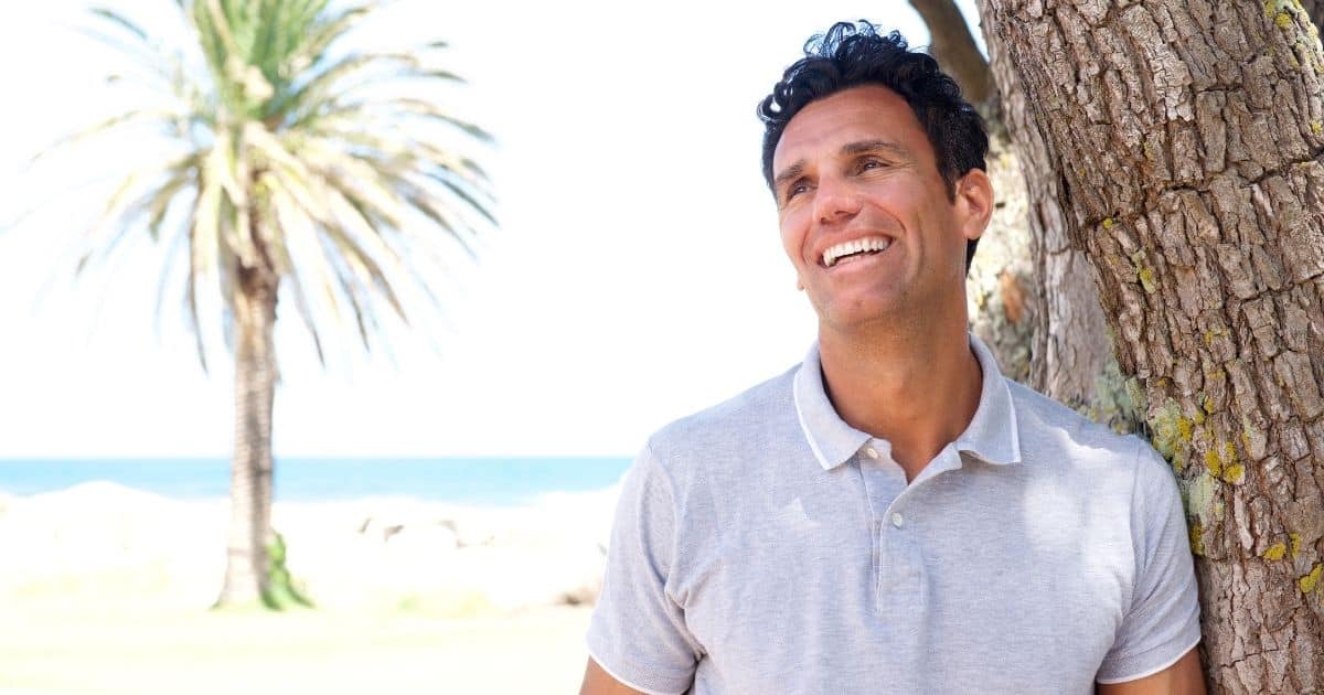 Smiling man near a palm tree