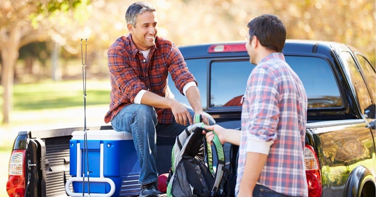 Two men packing coolers near a truck