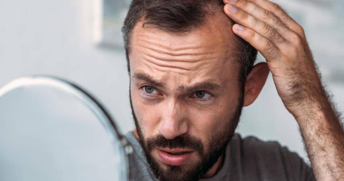 A Man Looking in a Mirror Examining his Baldness
