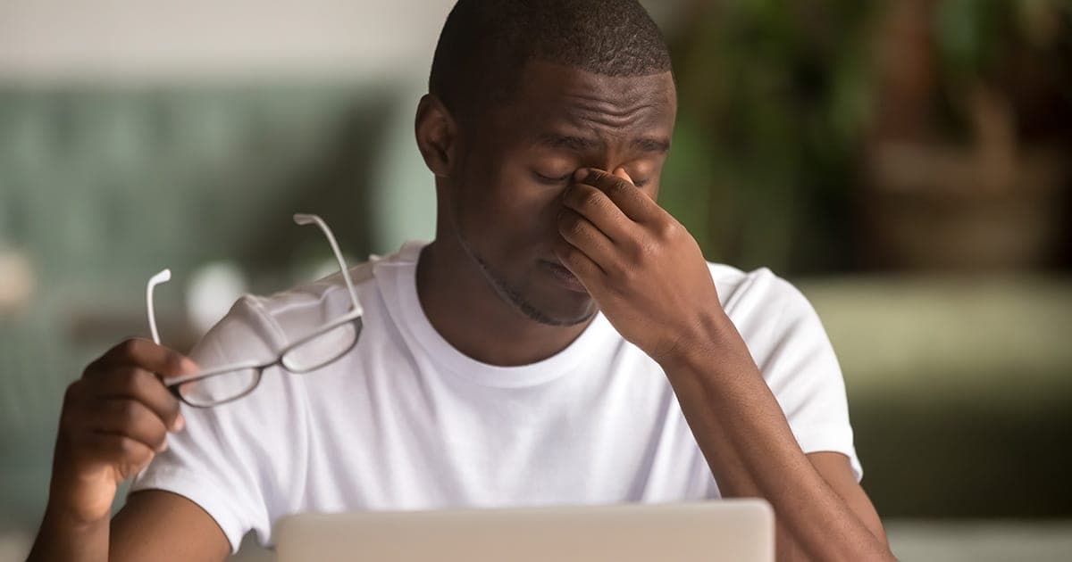 Tired man rubbing his eyes at a laptop