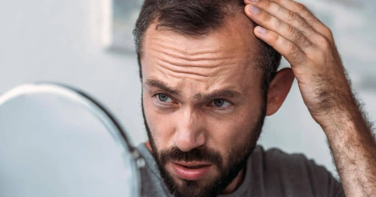 A Man Looking in a Mirror Examining his Baldness