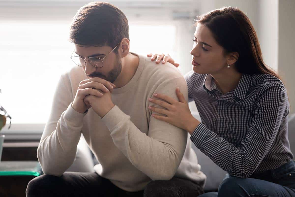 An anxious man sitting with a concerned woman