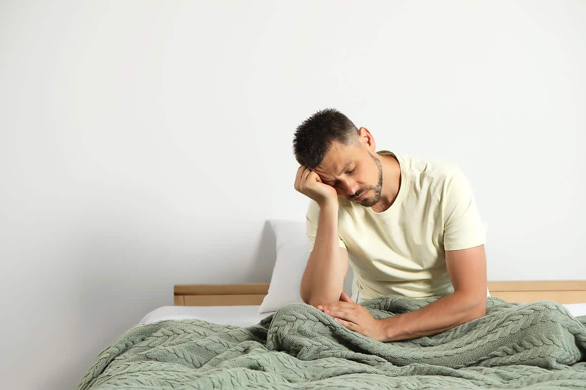 A tired man sitting in bed