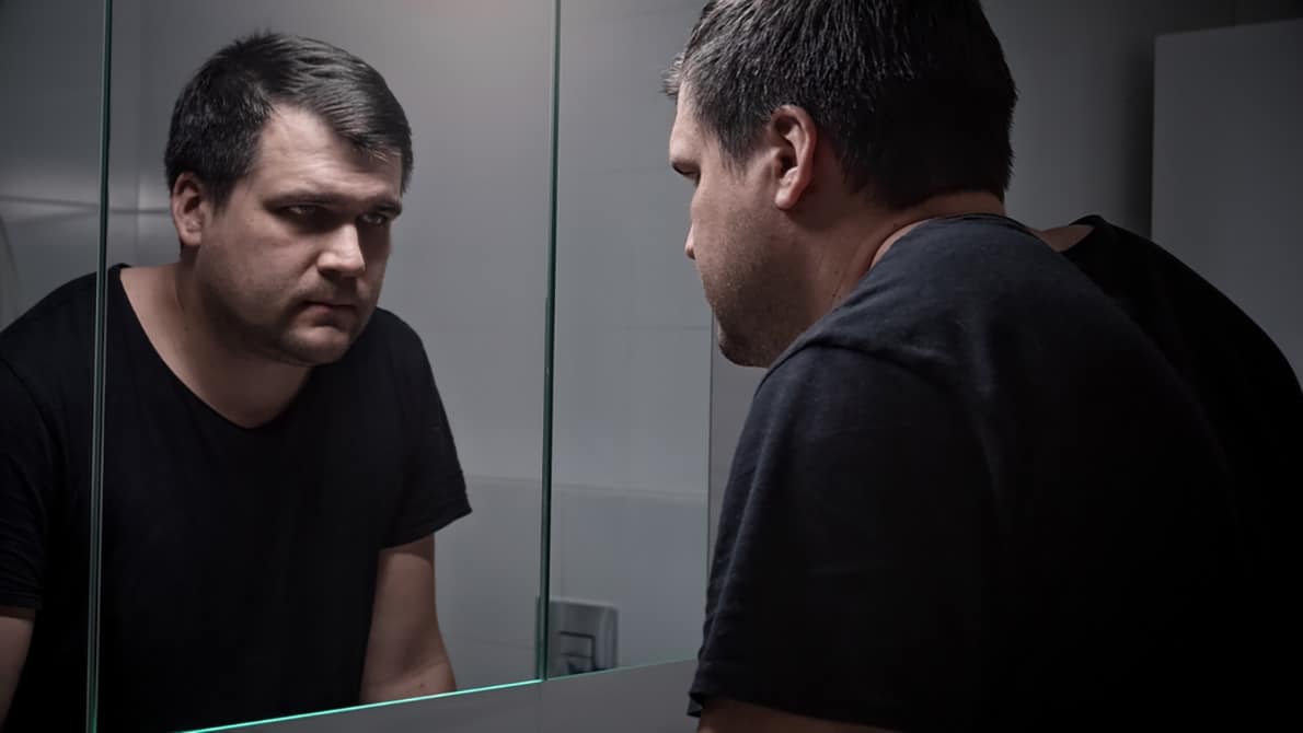 A depressed man looking in the mirror