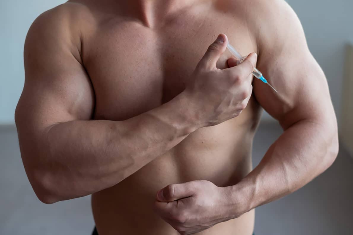 A muscular man giving himself an injection