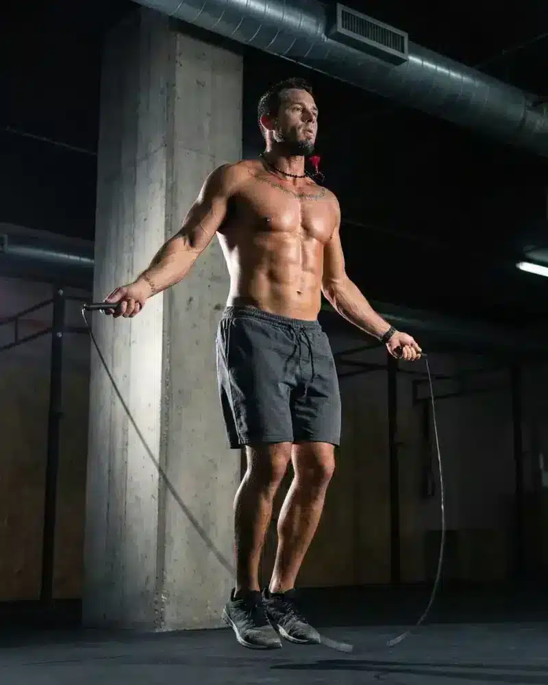 A fit man performs high-speed jump rope jumps, demonstrating physical energy and cardiovascular endurance.